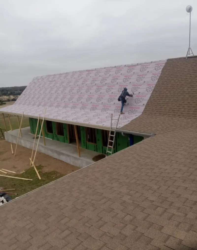 Worker preparing underlayment for a metal roof installation in Colusa